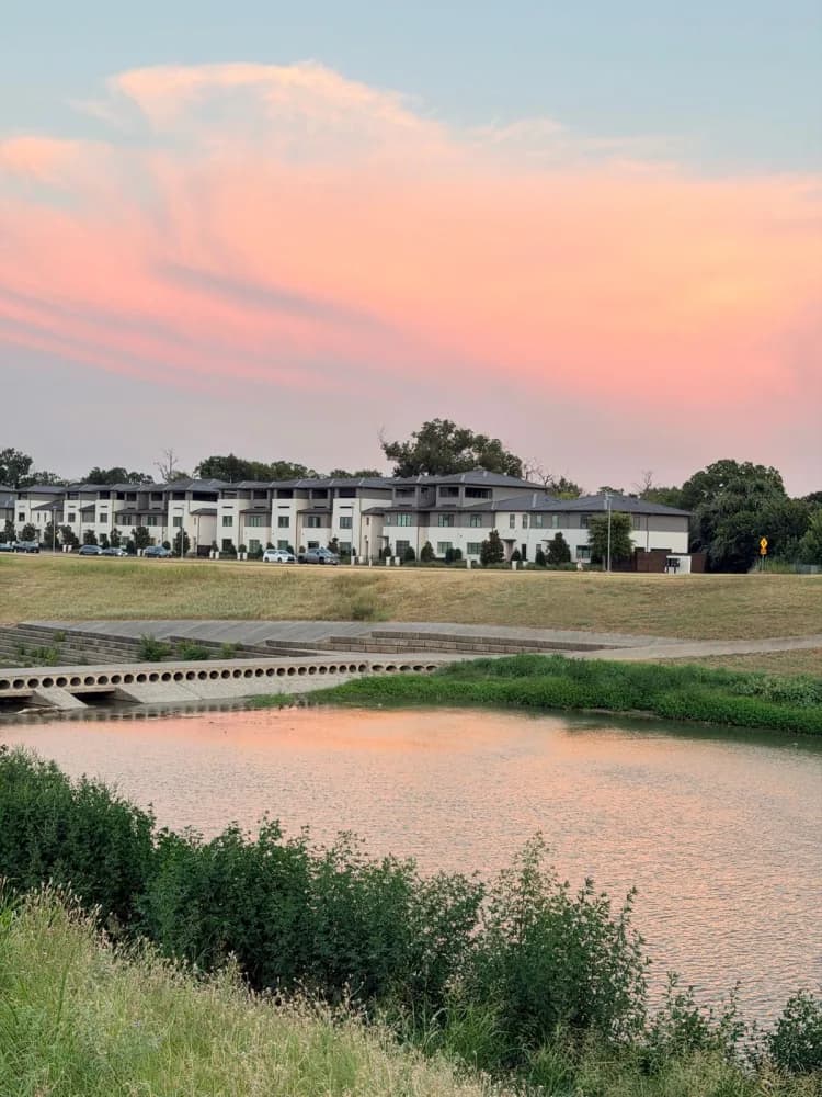 A pink sky over a river and the trail beside it in Fort Worth